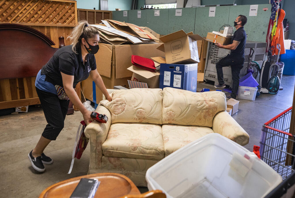 Marisol Mercato moves a piece of furniture that needs to be cleaned at the Redwood Gospel Mission Thrift Store in Santa Rosa. (John Burgess/The Press Democrat)