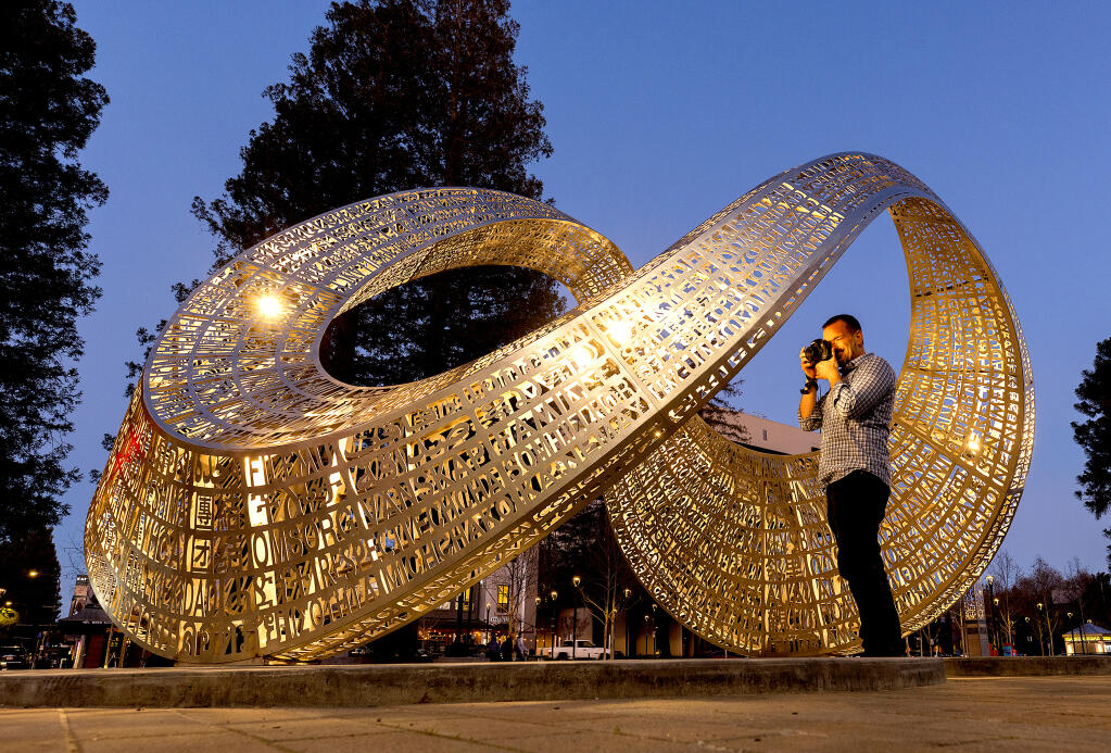 Maria Carrillo journalism teacher James Hart wanted to photograph the new sculpture “Unum” in the sunset light in Old Courthouse Square Wednesday, January 25, 2023. Meaning “oneness" or "together” in Latin, the piece is covered in words meant to represent the 32 different languages most commonly spoken in Sonoma County. (John Burgess/The Press Democrat)