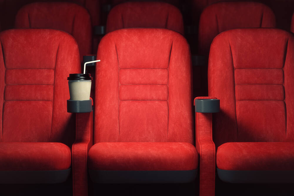 Cinema movie theater concept background. Red cinema seats and coffee or cola paper cup in empty theater. 3d illustration