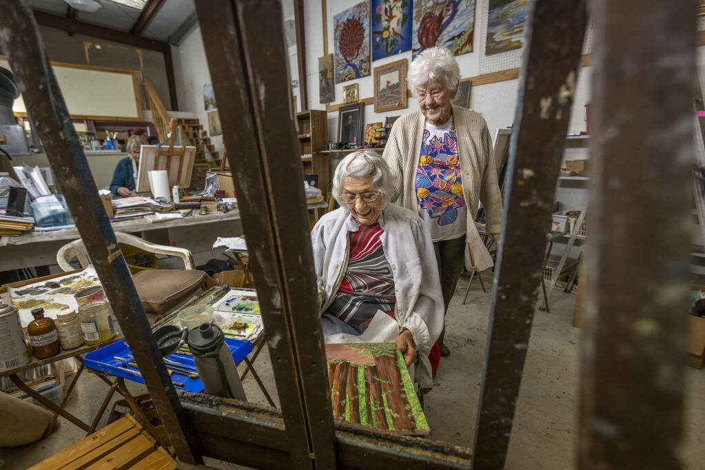 Ninety-nine-year-old painting teacher Adele Pruitt, right, looks over the process of a painting by her student, Jeanette Bylund, 93, in her Ukiah studio on Wednesday, December 15, 2021.  (Photo by John Burgess/The Press Democrat)