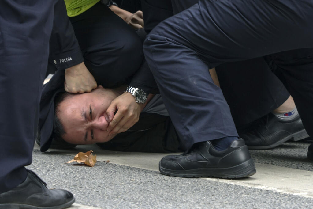 Chinese policemen pin down and detain a protester during a protest against anti-virus measures on a street in Shanghai, China on Nov. 27, 2022. China's sudden reopening after two years holding to a "zero-COVID" strategy left older people vulnerable and hospitals and pharmacies unprepared during the season when the virus spreads most easily, leading to many avoidable deaths, The Associated Press has found. (AP Photo, File)