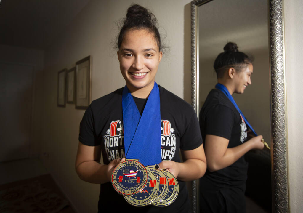 Sofia Iniguez, a seventeen-year-old Sonoma Valley High School senior who recently set state, national and world records for deadlifting 340+ pounds, at her home with a few of her medals on Wednesday, Nov. 25. (Photo by Robbi Pengelly/Index-Tribune)