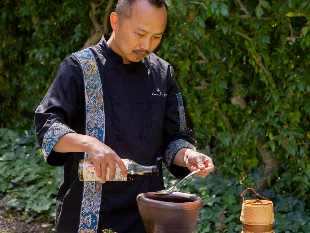 Chef Keo Xayavong adds fish sauce to Jeow Som, a Laotian hot and sour dipping sauce made using a large mortar with a wooden pestle to grind it. (John Burgess / The Press Democrat)