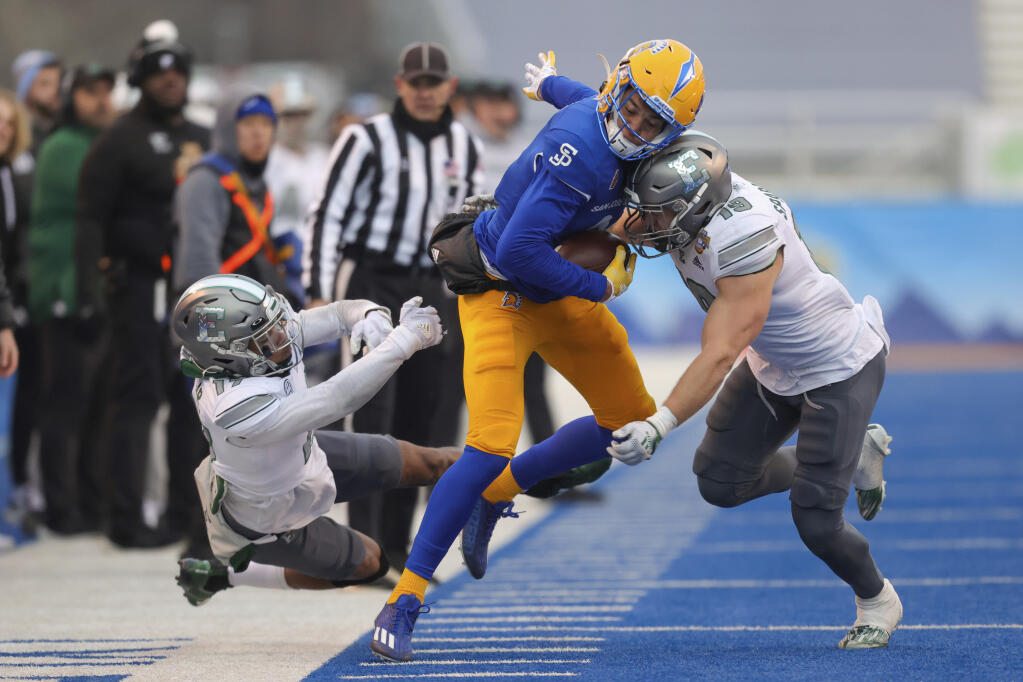 San Jose State wide receiver Elijah Cooks is hit by Eastern Michigan linebacker Joe Sparacio, right, after breaking away from defensive back Mark Lee Jr., left, on a reception during the second half of Tuesday’s Idaho Potato Bowl in Boise. (Steve Conner / ASSOCIATED PRESS)
