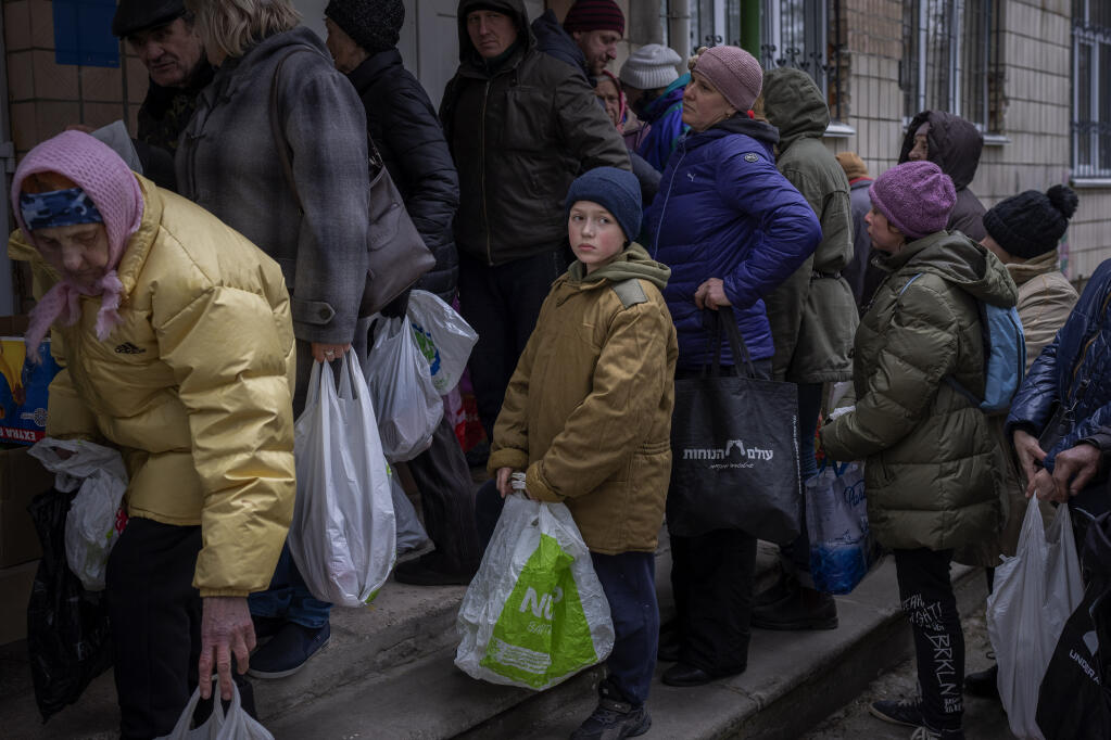 Sergei, 11, waits his turn to receive donated food during an aid humanitarian distribution in Bucha, in the outskirts of Kyiv, on Tuesday, April 19, 2022. Citizens of Bucha are still without electricity, water and gas after more than 44 days since the Russian invasion began. (AP Photo/Emilio Morenatti)