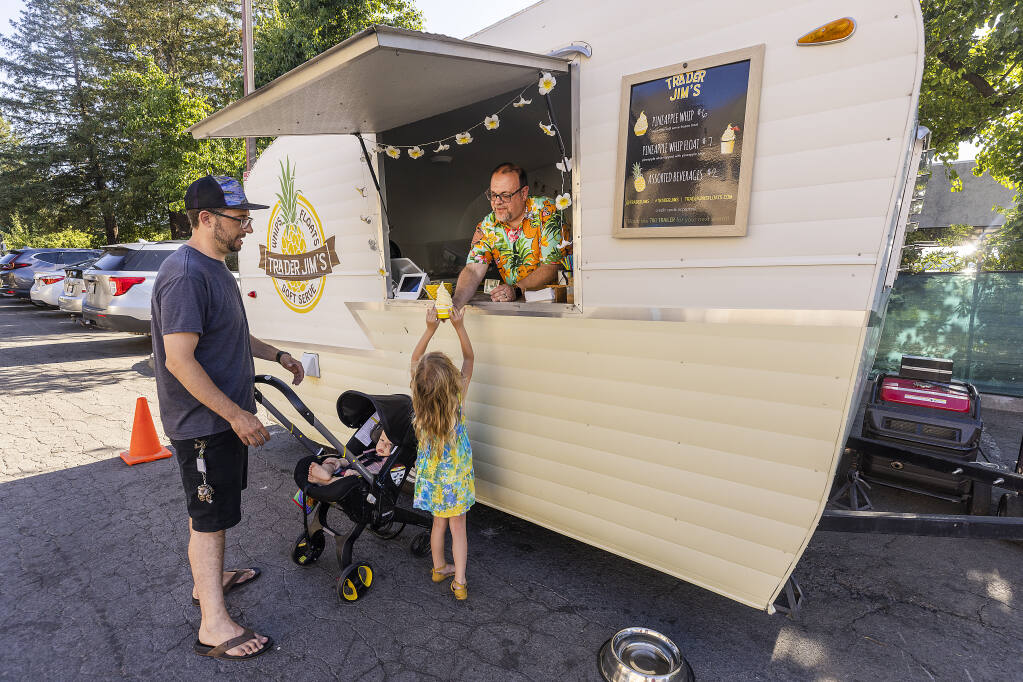 Craig Karas serves up pineapple whips to Jordyn Johnson, 4, and her dad Sam from his Trader Jim’s food truck parked at The Cooperage in Santa Rosa Tuesday, June 21, 2022.  (John Burgess / The Press Democrat)