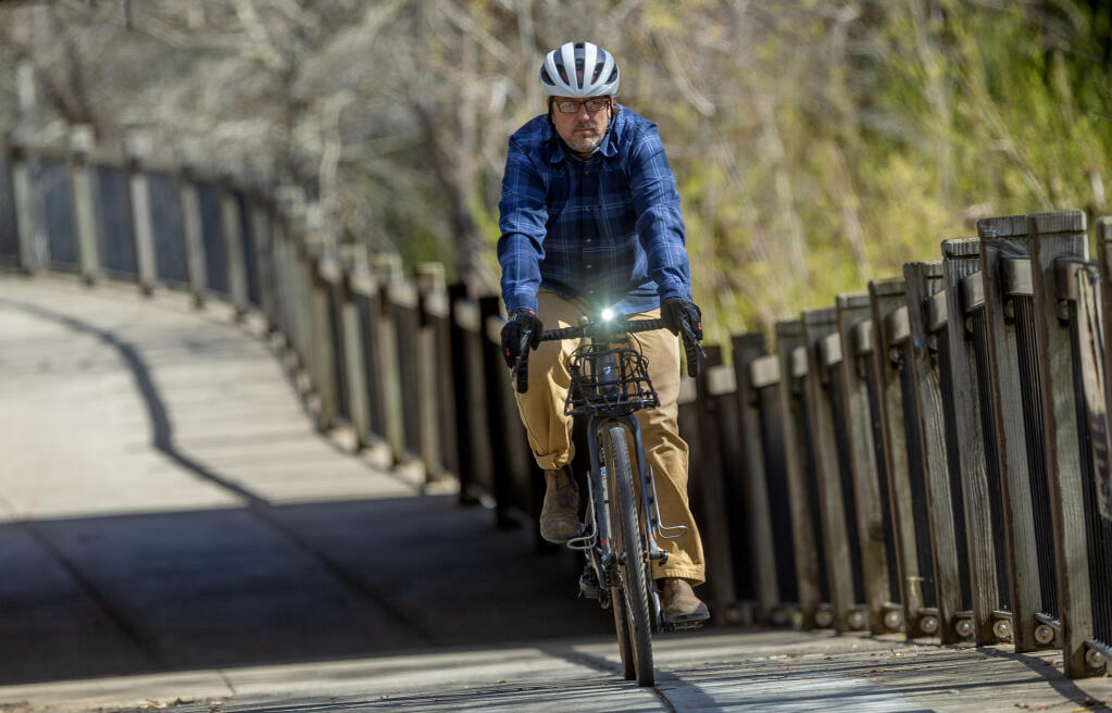 Jake Bayless, who three years ago was struck from behind by an impatient driver while riding his bike in West County, prefers to stick to trails and stay off streets now as he bikes the Prince Memorial Greenway on the way to his office in downtown Santa Rosa March 2, 2023. (Chad Surmick / The Press Democrat)