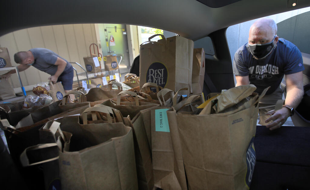 Preparing to make deliveries in Sonoma County, Dave Hendrickson of Sonoma, right, and Mike Bichanich of San Diego, load groceries in to Hendrickson's vehicle at Food For Thought in Forestville, Thursday, Oct. 29, 2020.  (Kent Porter / The Press Democrat)