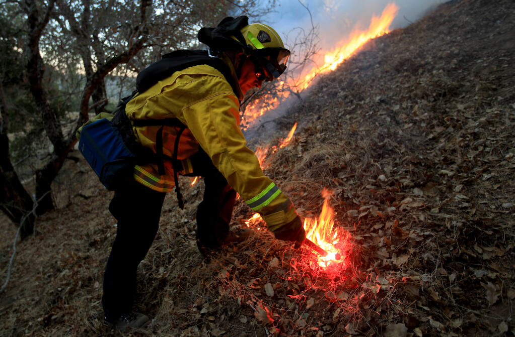 Mark Cia of Napa County Fire lights a backfire during the Pope fire in Napa County, Friday, Oct. 23, 2020.  (Kent Porter / The Press Democrat) 2020