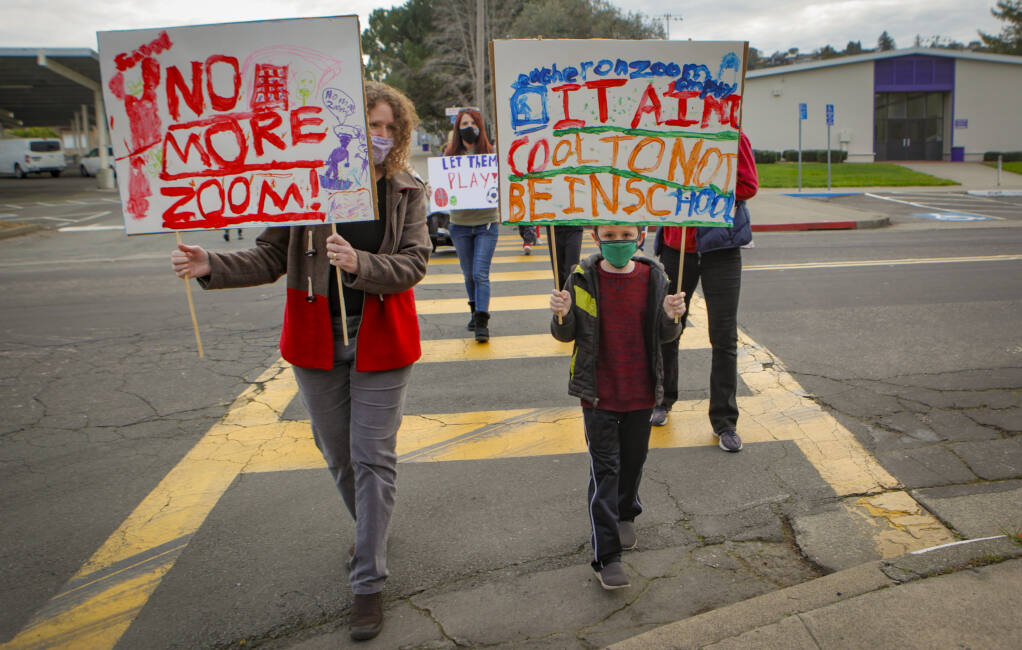 Karla Greschner and her son, Dean, 8, a second-grader at Old Adobe School, marched with other Petaluma students and parents to show their support for schools to reopen.(CRISSY PASCUAL/ARGUS-COURIER STAFF)