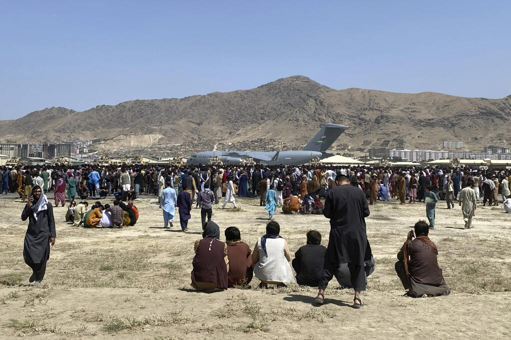 In this Aug. 16, 2021, file photo, hundreds of people gather near a U.S. Air Force C-17 transport plane at the perimeter of the international airport in Kabul, Afghanistan. (SHEKIB RAHMANI/ASSOCIATED PRESS)