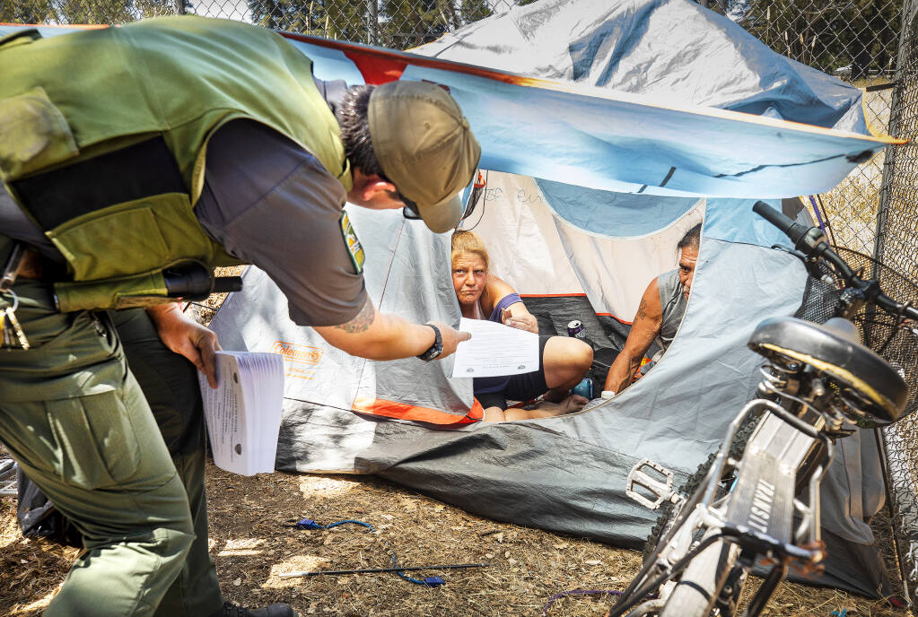 Park Ranger Josh Crosbie hands out an official “Notice to Vacate” to homeless in an encampment along the Joe Rodota trail in Santa Rosa July 22, 2022. (Photo by John Burgess)