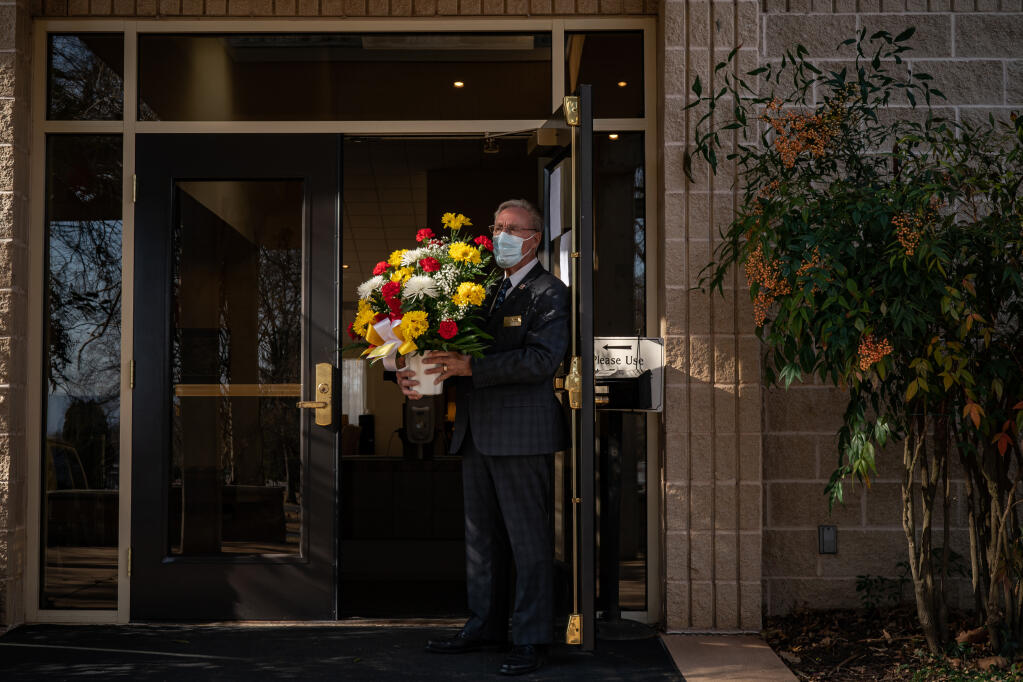 Ken Hammond, a funeral associate in Hagerstown, Maryland, holds flowers for the family of a man in his 50s who died of COVID-19 in January 2021. ( Salwan Georges / Washington Post)