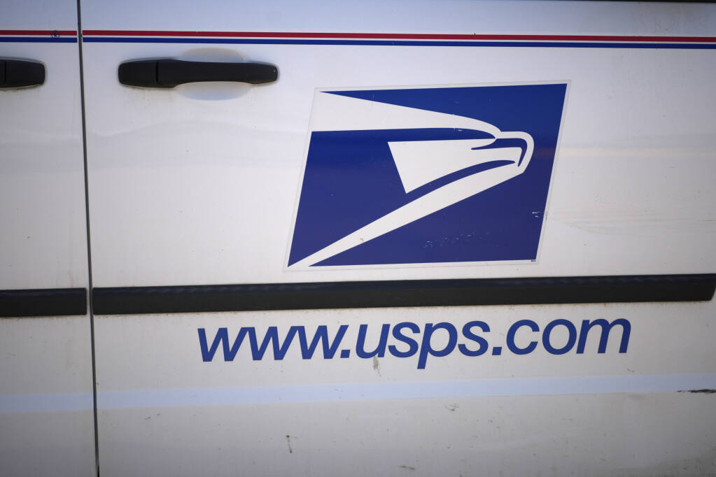 Logo for the United States Postal Service graces the side of a van parked at the main post office Sunday, Sept. 19, 2021, in Commerce City, Colo. (AP Photo/David Zalubowski)