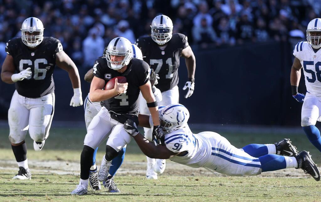 Oakland Raiders quarterback Derek Carr is tackled by Indianapolis Colts defensive tackle Hassan Ridgeway on a scramble during their game in Oakland on Saturday, Dec. 24. The Raiders defeated the Colts 33-25. (Christopher Chung / The Press Democrat)
