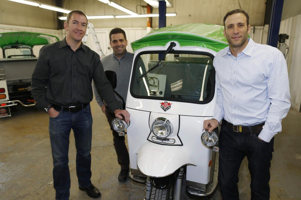 In this photograph taken Friday, Feb. 27, 2015, Colin Sommers, left, director of engineering for eTuk USA, Walid Mourtada, center, chief executive officer, and Michael Fox show off one of their company's electric Tuk-Tuk models being prepared for delivery at the trio's manufacturing plant in northeast Denver. It's too soon to know if Americans will embrace tuk-tuks, but Fox, director of sales and marketing for eTuk USA, says the company has been selling the vehicles across the country to individuals, marketing companies and food vendors for between $16,950 and $25,000, depending on how they are customized. (AP Photo/David Zalubowski)