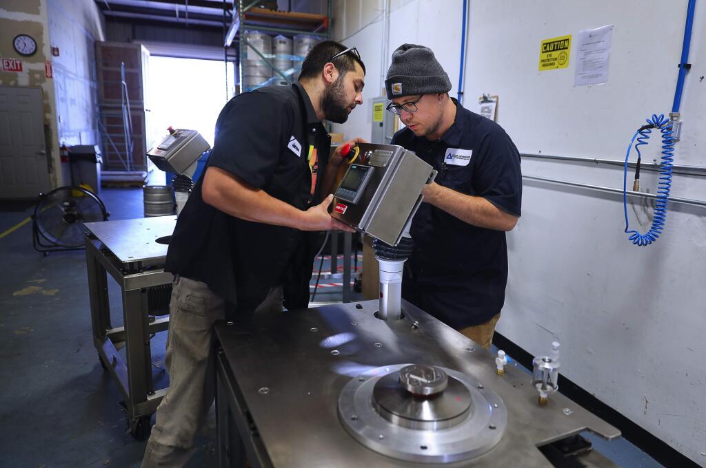 James Hewitson, left, and Adam Kellerman attach a control panel onto a centrifuge utility platform at Delta Separations, in Santa Rosa on Thursday, September 13, 2018. (Christopher Chung/ The Press Democrat)