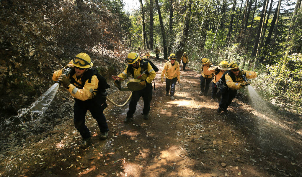 Sonoma County firefighter/paramedics, Rico Mendez, on left, with Andrew Negus; on right, Justin Pels, front and Eugene Stiponav, take part in wildland fire training on Tom Graham's property on St. Helena Road, Wednesday, May 5, 2021. September 2020's Glass fire burned about 12 acres of the property, left side of frame.  (Kent Porter / The Press Democrat) 2021