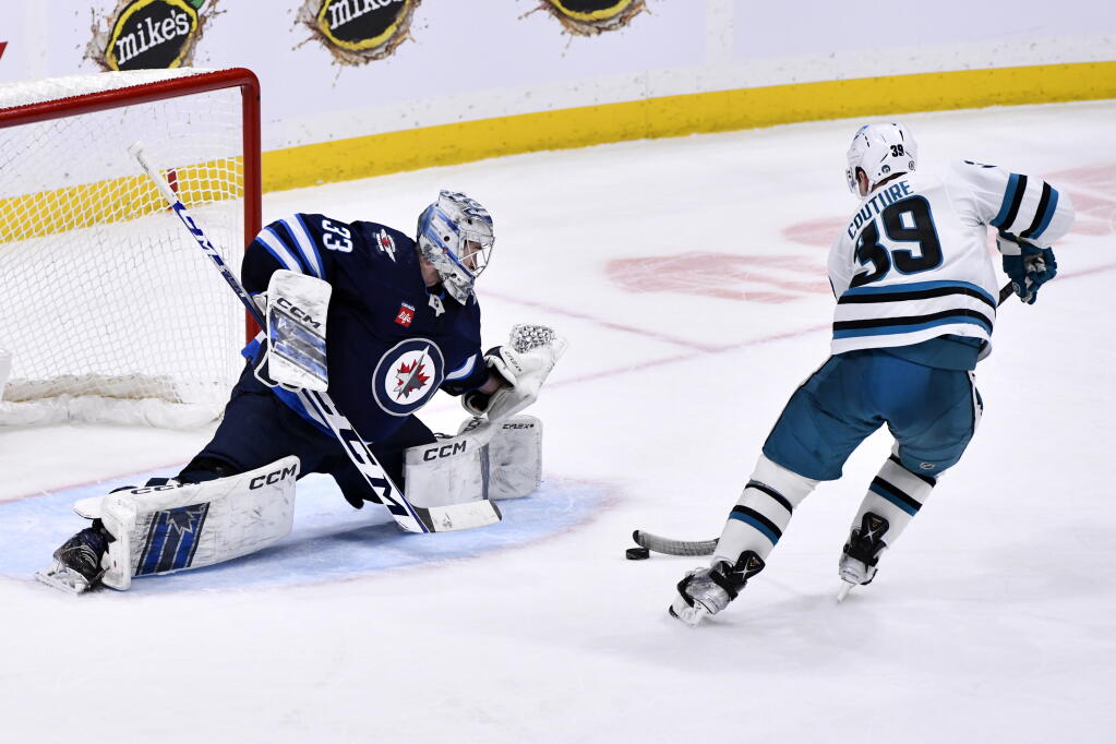San Jose Sharks' Logan Couture (39) scores on Winnipeg Jets goaltender David Rittich (33) during overtime of an NHL hockey game, in Winnipeg, Manitoba, on Monday March 6, 2023. (Fred Greenslade/The Canadian Press via AP)
