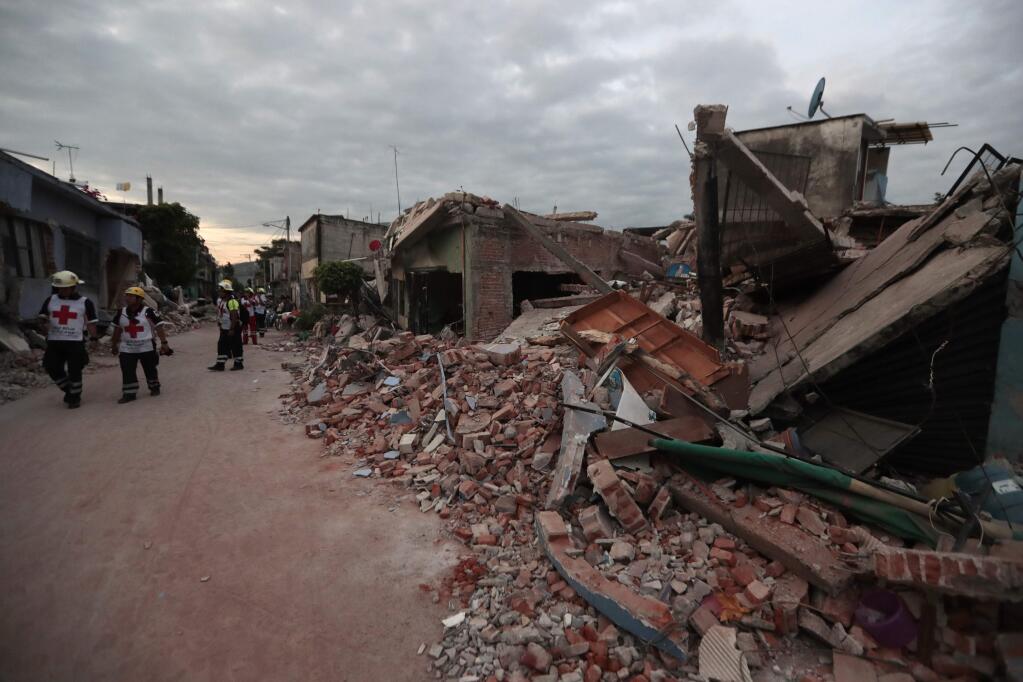 Red Cross workers walk next to buildings demolished by a 7.1 earthquake, in Jojutla, Morelos state, Mexico, Wednesday, Sept. 20, 2017. Police, firefighters and ordinary Mexicans are digging frantically through the rubble of collapsed schools, homes and apartment buildings, looking for survivors of Mexico's deadliest earthquake in decades as the number of confirmed fatalities climbed to 248. (AP Photo/Eduardo Verdugo)