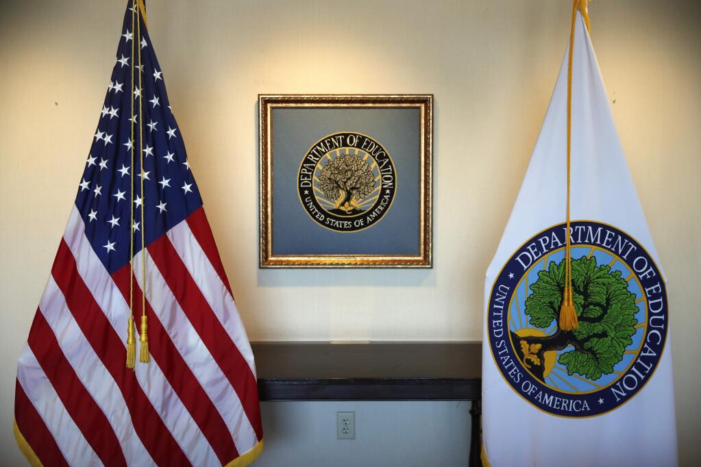 In this Aug. 9, 2017, photo, flags decorate a space outside the office of Education Secretary Betsy DeVos, at the Education Department in Washington. The U.S. Education Department is warning America's universities that they must accurately report money coming from foreign nations or risk facing federal investigations, fines and legal action. (AP Photo/Jacquelyn Martin)