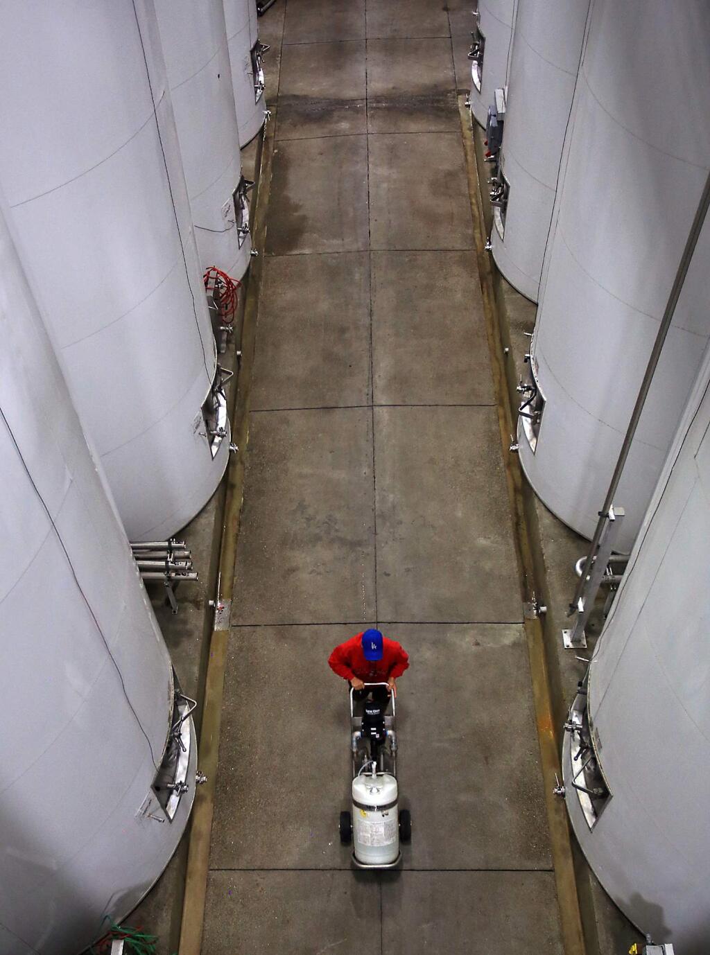 Fetzer cellar worker Jose Moreno moves a water saving sanitizer in to position past polar clad wrapped wine tanks, both energy and water saving measures at Fetzer Vineyards in Hopland, Tuesday Oct. 20, 2015. (Kent Porter / Press Democrat) 2015
