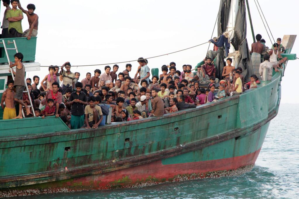Migrants sit on their boat as they wait to be rescued by Acehnese fishermen on the sea off East Aceh, Indonesia, Wednesday, May 20, 2015. Hundreds of migrants stranded at sea for months were rescued and taken to Indonesia, officials said Wednesday, the latest in a stream of Rohingya and Bangladeshi migrants to reach shore in a growing crisis confronting Southeast Asia. (AP Photo/S. Yulinnas)