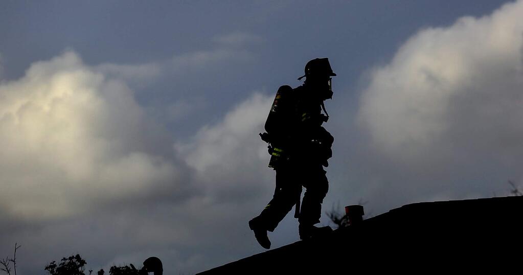 A Santa Rosa firefighter scales a roof a home and a garage that sustained fire damage on Hoen Ave. in Santa Rosa, Thursday Feb 16, 2017 (Kent Porter / The Press Democrat) 2017