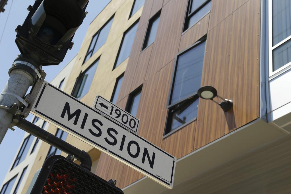 A street sign hangs outside a new apartment building on Mission Street, Tuesday, June 2, 2015, in San Francisco. Finding a place to live has become so expensive and emotional that city supervisors are considering a 45-day moratorium on luxury housing in the Mission District, which has long been one of the most diverse neighborhoods in the city. (AP Photo/Eric Risberg)