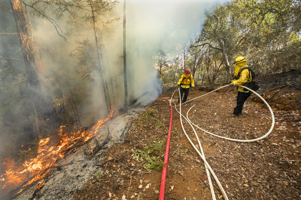 Cal Fire firefighters Allison Bailey, right, and Brion Borba untangle hoses along the edge of an 11-acre prescribed burn in the hills above the Dry Creek Valley on Thursday, Dec. 3, 2020. (John Burgess / The Press Democrat)