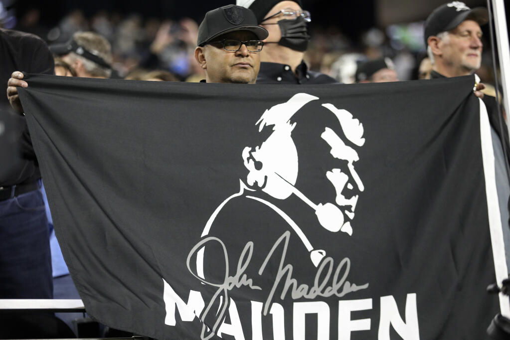 A Las Vegas Raiders fan holds a John Madden flag during the first half of an NFL football game, Sunday, Jan. 9, 2022, in Las Vegas. (AP Photo/Ellen Schmidt)