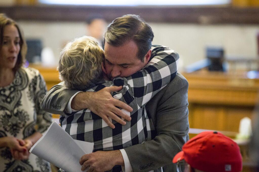 In a Tuesday, April 17, 2018 photo, Cincinatti Mayor John Cranley hugs a member of Kyle Plush's family before council's Law and Public Safety Committee meeting where Kyle Plush's death after he accidentally got pinned in the fold-away back seat of a minivan was discussed inside the Council Chambers at City Hall in Cincinnati. (Meg Vogel/The Cincinnati Enquirer via AP)