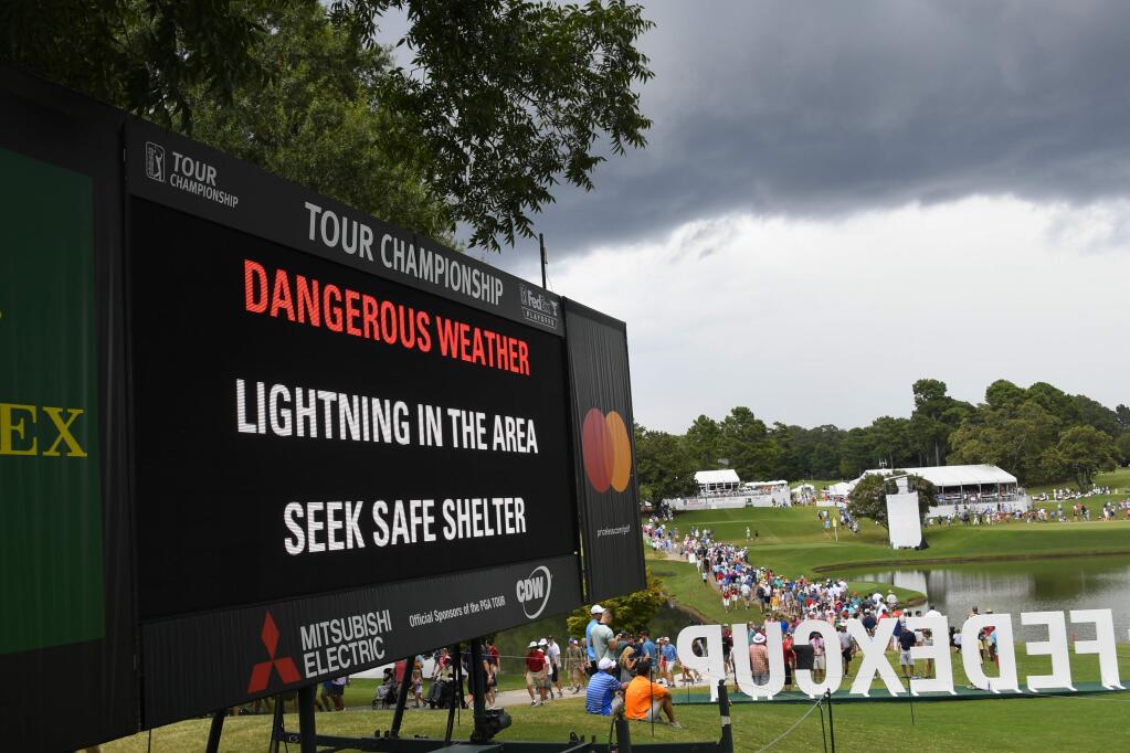 A sign warns of inclement weather as fans come off the course after a delay was called during the third round of the Tour Championship golf tournament Saturday, Aug. 24, 2019, in Atlanta. (AP Photo/John Amis)