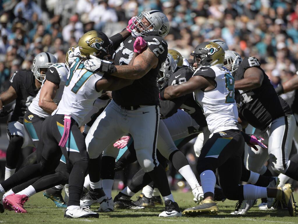 In this Oct. 23, 2016, file photo, Oakland Raiders tackle Donald Penn, center, blocks against Jacksonville Jaguars strong safety Johnathan Cyprien during a game in Jacksonville, Fla. (AP Photo/Phelan M. Ebenhack, File)