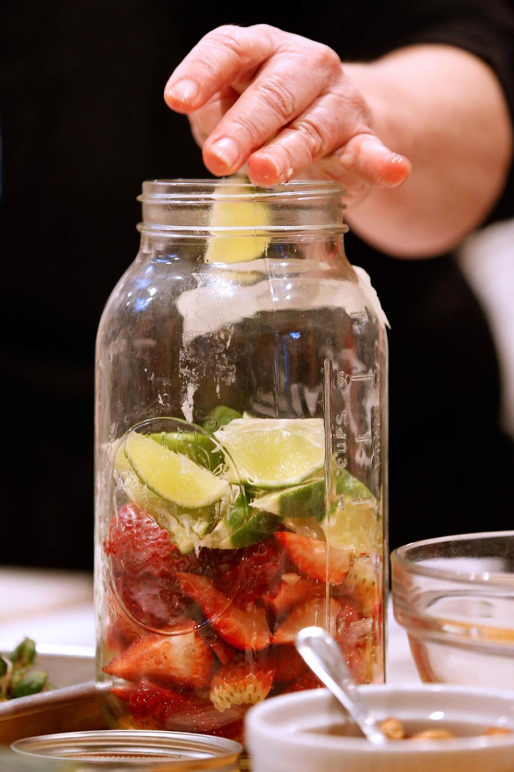 Tami Henris drops lime slices into a jar with strawberries to make a strawberry balsamic smash cocktails during a springtime cocktail party class with chef Julie Steinfeld at Ramekins culinary school in Sonoma, California, on Thursday, April 19, 2018. (Alvin Jornada / The Press Democrat)