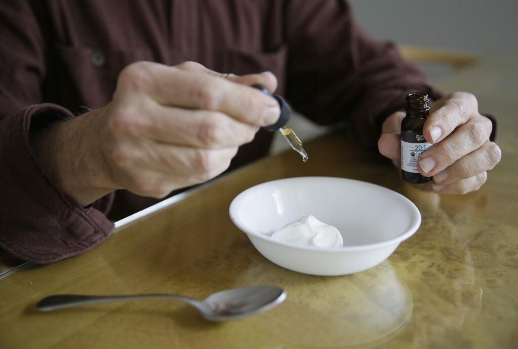 In this photo taken Wednesday, Feb. 15, 2017, Michael Fasman adds a cannabis tincture to his dog's yogurt at his home in San Francisco. As more states legalize marijuana for humans, more pet owners are giving their furry companions cannabis-based extracts, ointments and edibles marketed to treat everything from arthritis and anxiety to seizures and cancer. (AP Photo/Eric Risberg)