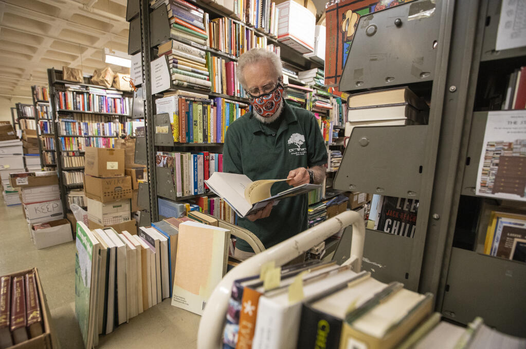Library volunteer Dick Wilhelm sorts books in preparation for this weekend’s annual book fair at the downtown Santa Rosa Public Library on Wednesday, March 30, 2022. (Chad Surmick / The Press Democrat)