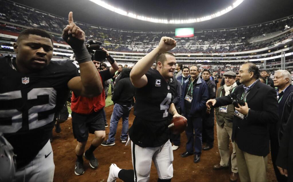 In this Nov. 21, 2016, file photo, Oakland Raiders quarterback Derek Carr, center, and defensive end Khalil Mackleave the field after a game against the Houston Texans in Mexico City. The Raiders return to Mexico City to face the New England Patriots this week. (AP Photo/Eduardo Verdugo, File)