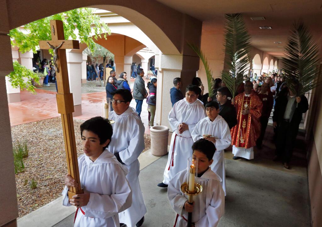 Altar boys followed by Father Michaelraj Philominsamy (in red vestments) and members of the church congregation walk in a Palm Sunday procession around the courtyard at Our Lady of Guadalupe Catholic Church in Windsor, California on Sunday, March 20, 2016. (Alvin Jornada / The Press Democrat)