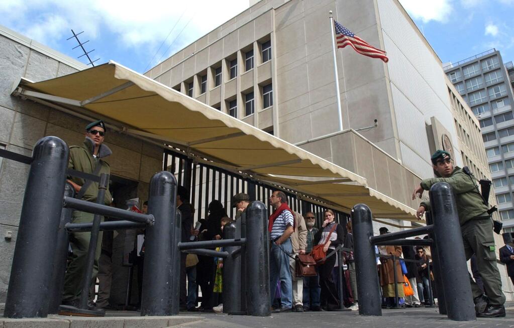 FILE - In this March 17, 2003, file photo, an Israeli border policemen guards the U.S. Embassy in Tel Aviv as other Israelis line up for U.S. visas. (AP Photo/Eitan Hess-Ashkenazi, File)