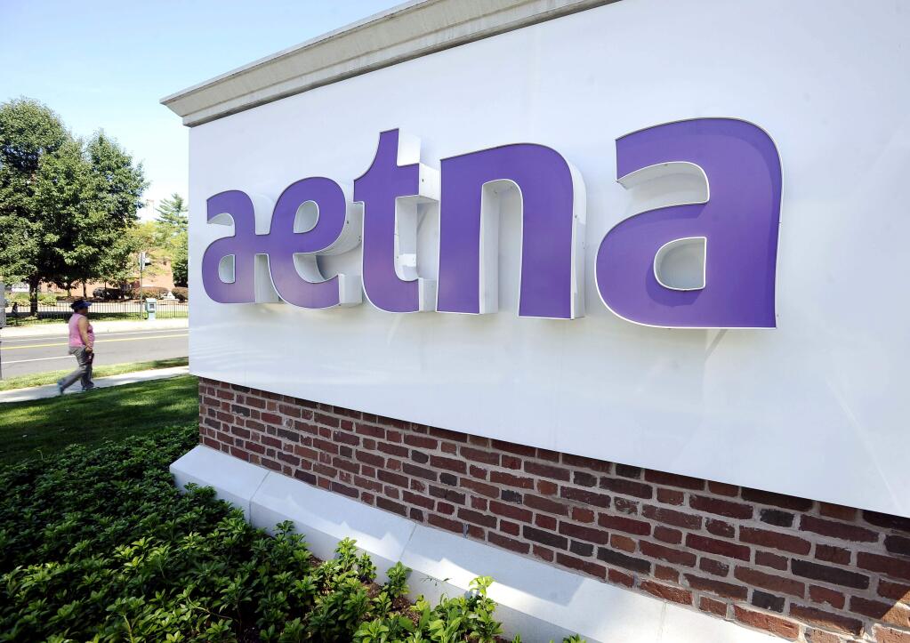 In this Tuesday, Aug. 19, 2014, photo, a pedestrian walks past a sign for Aetna Inc., at the company headquarters in Hartford, Conn. Aetna will become the latest health insurer to chop its participation in the Affordable Care Act's public exchanges when it trims its presence to four states for 2017, from 15 this year. The nation's third-largest insurer said late Monday, Aug. 15, 2016, that a second-quarter pre-tax loss of $200 million from its individual insurance coverage helped it decide to limit exposure to the exchanges, which also have generated losses for UnitedHealth Group and Anthem, among other carriers. (AP Photo/Jessica Hill)