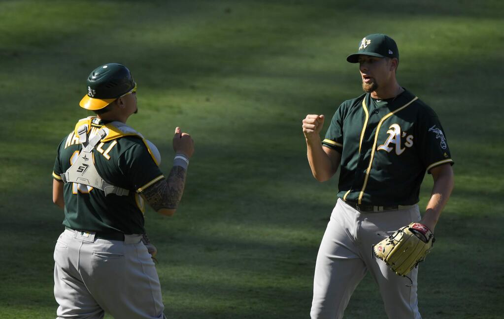 Oakland Athletics catcher Bruce Maxwell, left, and relief pitcher Blake Treinen congratulate each other after they defeated the Los Angeles Angels in a baseball game, Sunday, Aug. 6, 2017, in Anaheim, Calif. (AP Photo/Mark J. Terrill)