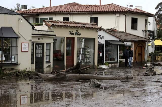 FILE - In this Jan. 9, 2018 file photo Debris and mud cover the street in front of local area shops after heavy rain brought flash flooding in Montecito, Calif. A Southern California utility has agreed to pay $360 million to settle lawsuits brought by cities, counties and other public agencies over deadly wildfires sparked by its equipment in the last two years, including one that was later blamed for a mudslide that killed more than 20 people. An attorney for 23 public entities said Wednesday, Nov. 13, 2019, that Southern California Edison has agreed to the sum to repay taxpayers for firefighting and damage from the Thomas Fire in 2017 and Woolsey Fire last year. (Daniel Dreifuss,File)
