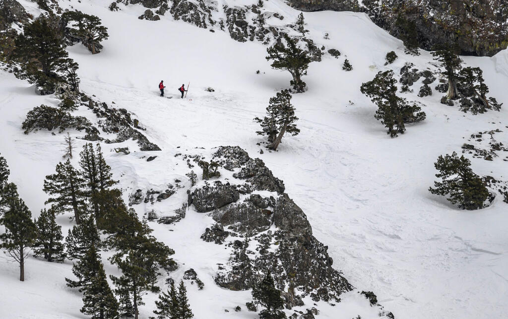 FILE - Two members of the ski patrol investigate the top of the avalanche zone on the Subway run where one person was killed and another seriously injured Friday, Jan. 17, 2020, at Alpine Meadows Ski Resort near Lake Tahoe, Calif. Since December 2022, a parade of a dozen atmospheric storms have dumped so much snow up and down the Sierra that several ski resorts around Lake Tahoe have had to shut down multiple times. The National Weather Service in Reno recently called it the "winter that just doesn't want to end." (Jason Pierce/The Sacramento Bee via AP, File)