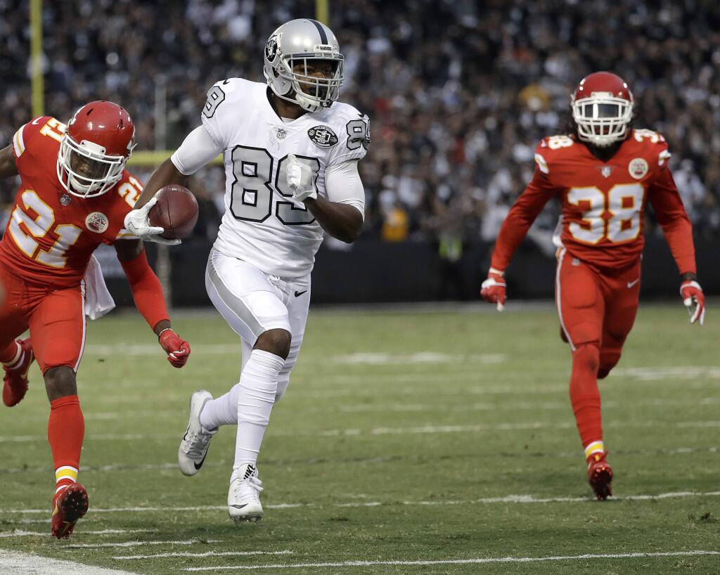 In this Oct. 19, 2017, file photo, Oakland Raiders wide receiver Amari Cooper runs past Kansas City Chiefs cornerback Eric Murray (21) and defensive back Ron Parker (38) to score a touchdown during the first half in Oakland. (AP Photo/Marcio Jose Sanchez, File)