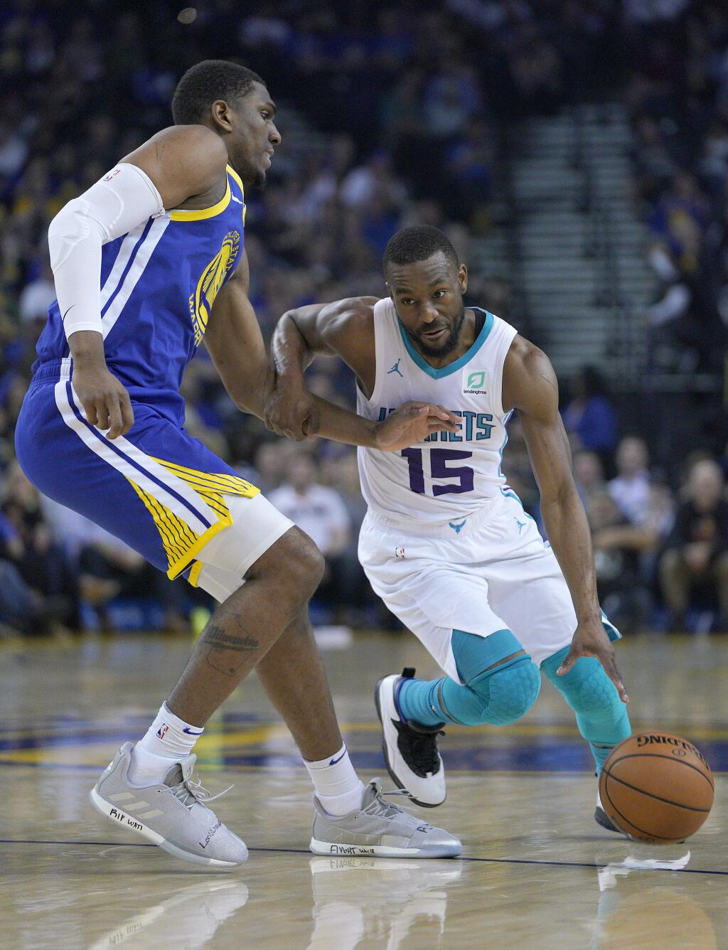 Charlotte Hornets guard Kemba Walker, right, dribbles past Golden State Warriors center Kevon Looney, left, during the first half of an NBA basketball game Sunday, March 31, 2019, in Oakland, Calif. (AP Photo/Tony Avelar)