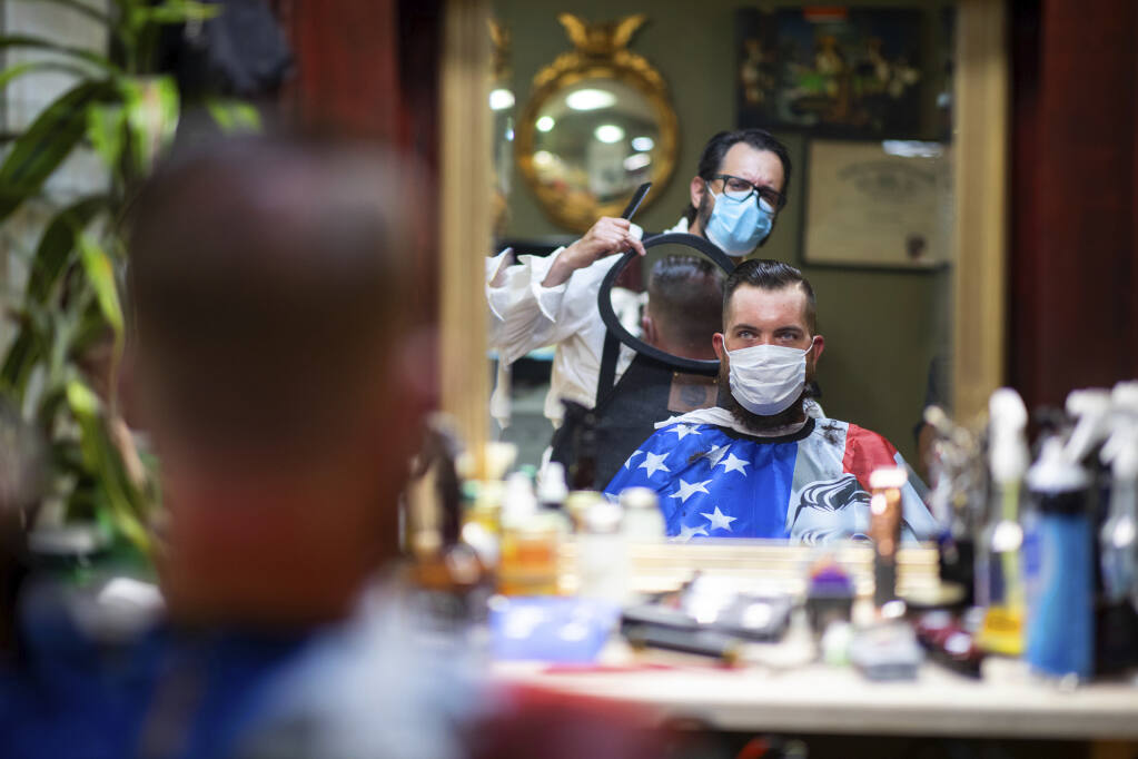 FILE - In this Friday, June 26, 2020 file photo, Barber Mike McAndrew holds a mirror as customer Rob Verrastro looks at his new haircut at Three Saints Barbershop and Shave Parlor in Jessup, Pa. Restaurants, retailers and salons are desperately trying to stay afloat as the U.S. economy reopens in fits and starts after months in a coronavirus lockdown. But billions of dollars allocated by Congress as a lifeline to those very businesses are about to be left on the table when the government's Paycheck Protection Program stops accepting applications for loans Tuesday, June 29. (Christopher Dolan/The Times-Tribune via AP, File)