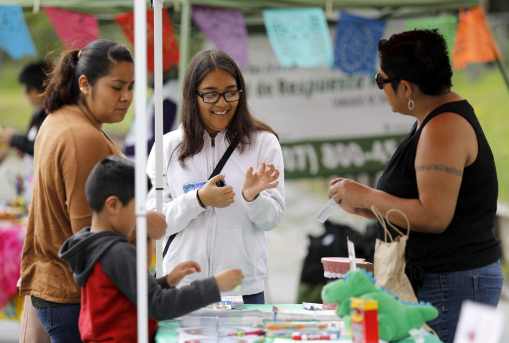 Geraldine Hernandez, 15, center, her mother Elisa Gordillo, and brother Salvador Hernandez, 6, talk with Wendy Lopez, right, of the PDI Surgery Center about dental hygiene during a Oaxacan Carnival and Health Fair event at the Healdsburg Community Center in Healdsburg, California  on Sunday, April 7, 2019. (BETH SCHLANKER/The Press Democrat)