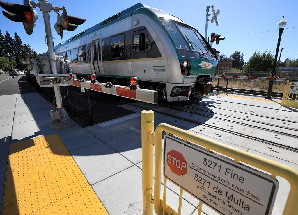 A pedestrian crossing arm is lowered as a SMART train at the downtown Santa Rosa station in Railroad Square passes by, Monday, Sept. 10, 2018.  (Kent Porter / The Press Democrat) 2018