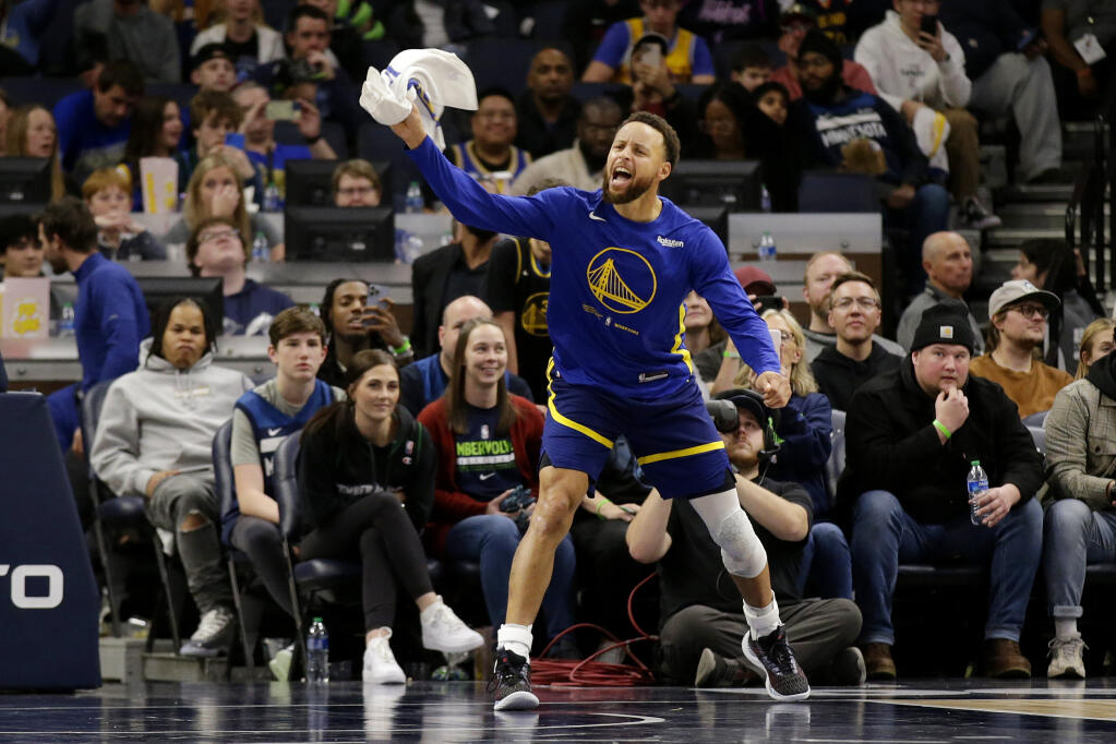 Golden State Warriors guard Stephen Curry cheers from the sideline during the fourth quarter of the team's NBA basketball game against the Minnesota Timberwolves on Sunday, Nov. 27, 2022, in Minneapolis. Curry was called for a technical foul. (AP Photo/Andy Clayton-King)